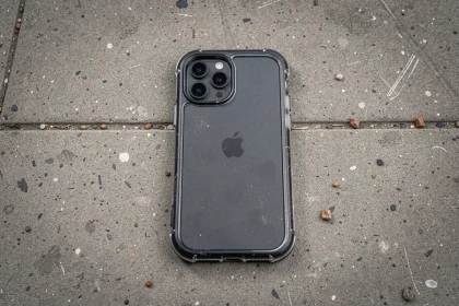 Coque de protection transparente pour iPhone 15 Pro posée sur un trottoir en béton après une chute, vue de dessus